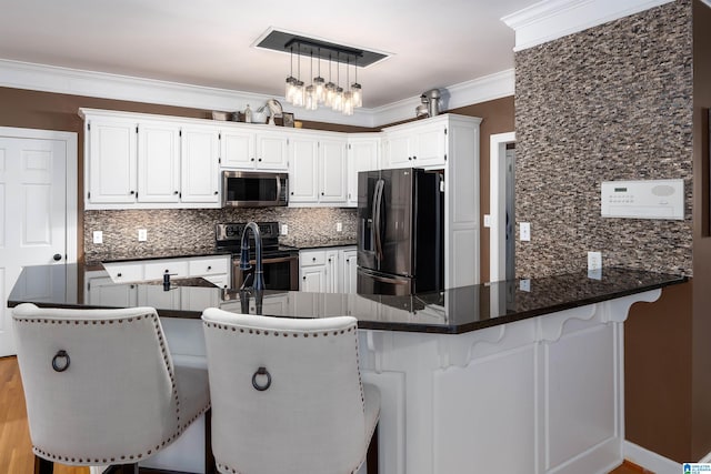 kitchen featuring white cabinetry, stainless steel appliances, kitchen peninsula, decorative backsplash, and ornamental molding