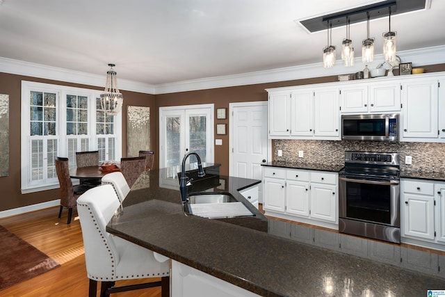 kitchen with pendant lighting, white cabinetry, and stainless steel appliances