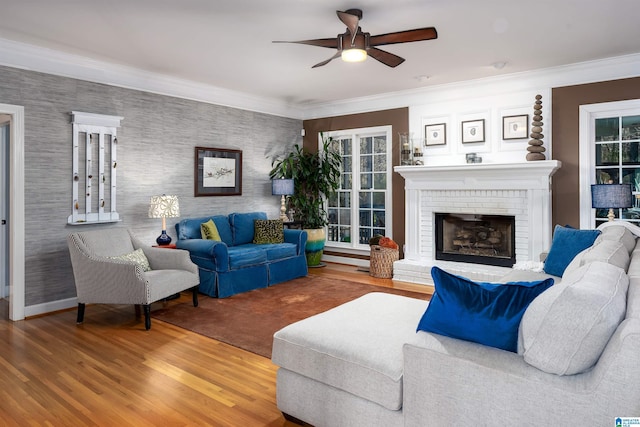 living room with ceiling fan, a fireplace, ornamental molding, and hardwood / wood-style flooring