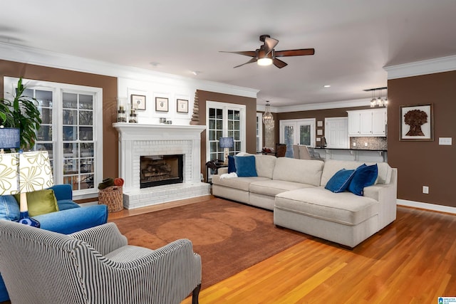 living room with french doors, ceiling fan, crown molding, wood-type flooring, and a fireplace