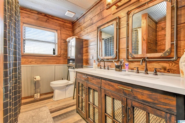 bathroom featuring wood walls, hardwood / wood-style floors, vanity, and toilet