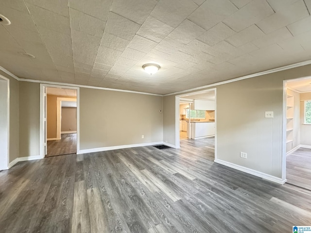 spare room with dark hardwood / wood-style flooring and crown molding