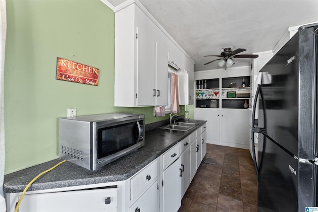 kitchen featuring white cabinets, ceiling fan, black refrigerator, and sink