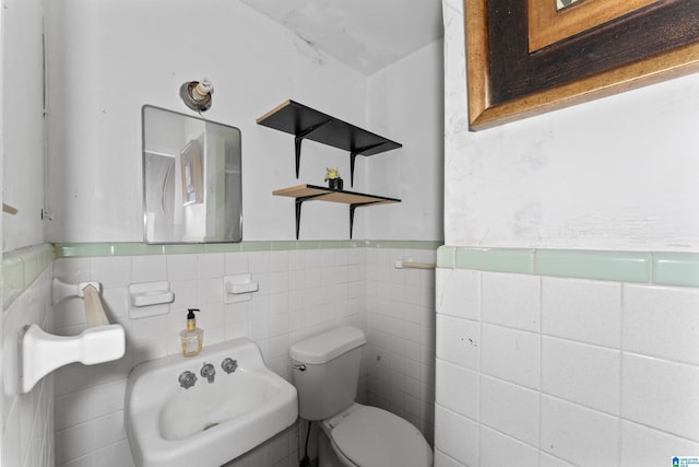 bathroom featuring sink, tile walls, and toilet