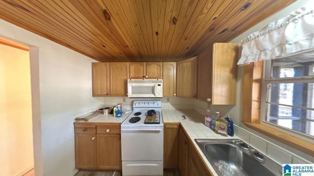 kitchen featuring tile counters, white appliances, and sink