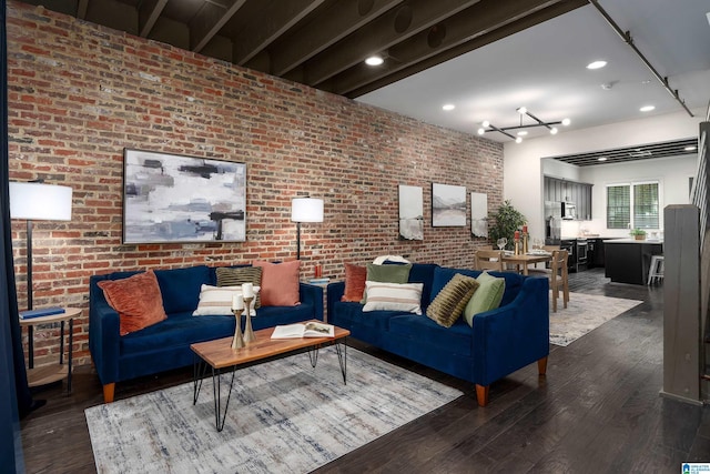 living room featuring dark hardwood / wood-style flooring, brick wall, and a chandelier