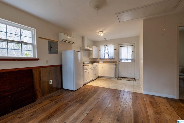 kitchen with white appliances, a healthy amount of sunlight, light hardwood / wood-style flooring, an AC wall unit, and white cabinetry