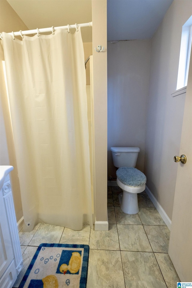 bathroom with tile patterned floors, curtained shower, and toilet