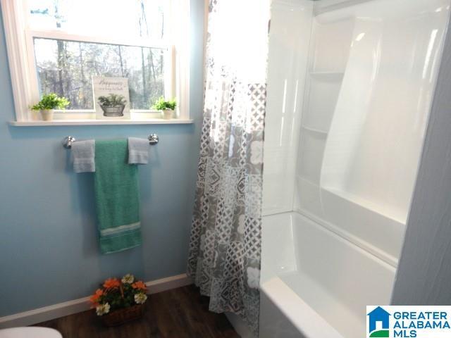 bathroom with hardwood / wood-style floors and shower / bath combo with shower curtain