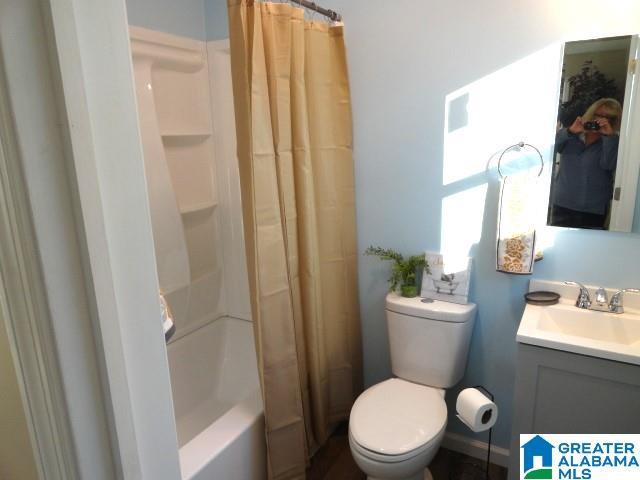 full bathroom with vanity, shower / bath combination with curtain, and toilet