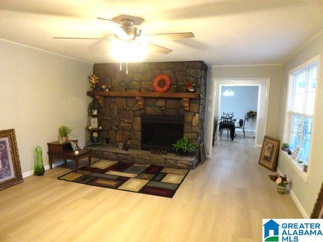 living room featuring wood-type flooring, ornamental molding, ceiling fan, and a fireplace