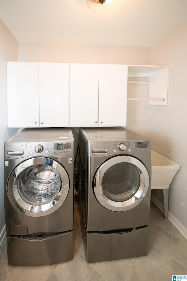 laundry room with cabinets, light tile patterned floors, and washing machine and dryer