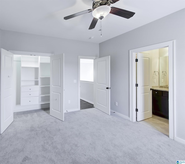 unfurnished bedroom featuring light carpet, ensuite bathroom, and ceiling fan