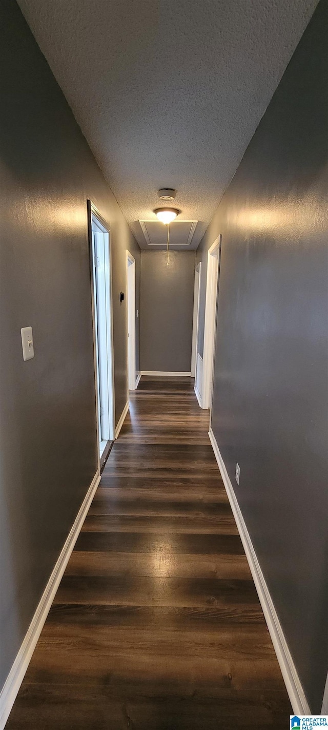 corridor featuring a textured ceiling and dark hardwood / wood-style flooring