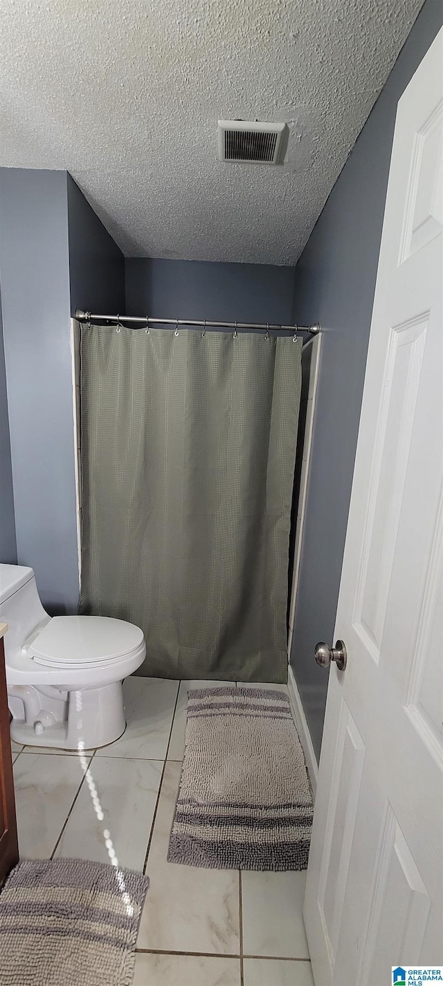 bathroom with toilet, tile patterned flooring, and a textured ceiling