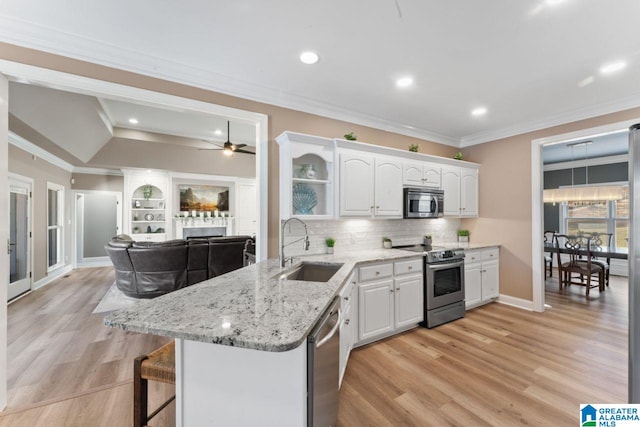 kitchen with ornamental molding, stainless steel appliances, ceiling fan, sink, and white cabinetry