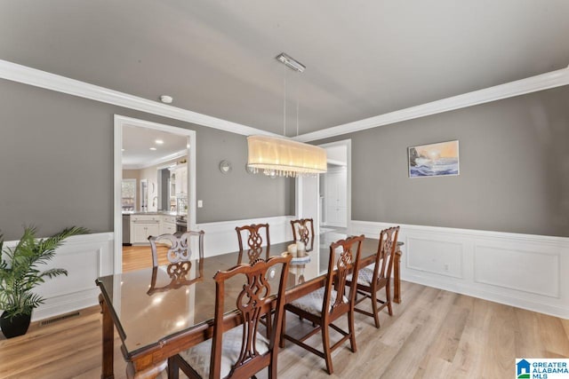 dining area featuring light hardwood / wood-style floors and crown molding