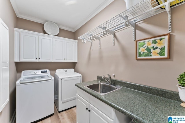 laundry room with sink, cabinets, ornamental molding, washer and clothes dryer, and light wood-type flooring