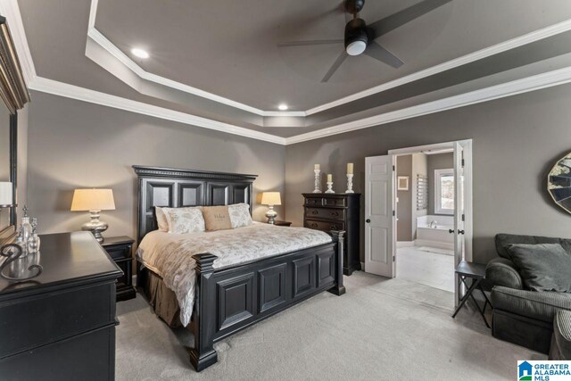 carpeted bedroom with ensuite bath, a raised ceiling, ceiling fan, and crown molding