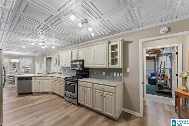 kitchen featuring decorative backsplash, stainless steel appliances, sink, pendant lighting, and cream cabinetry