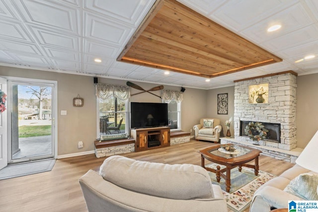 living room with a fireplace, light hardwood / wood-style floors, and a raised ceiling