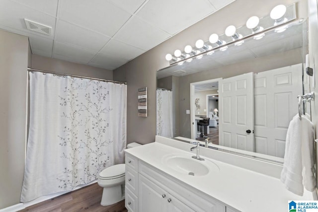 bathroom featuring a paneled ceiling, vanity, a shower with shower curtain, toilet, and wood-type flooring