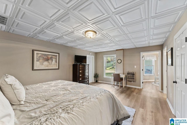 bedroom featuring heating unit and light hardwood / wood-style flooring