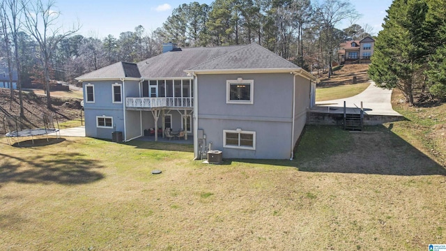 back of house featuring a yard, a trampoline, and central AC unit