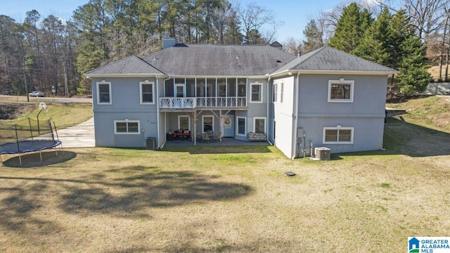 rear view of house featuring a lawn, a patio area, central AC, and a trampoline