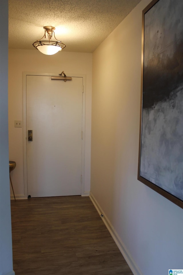 hall with a textured ceiling and dark wood-type flooring