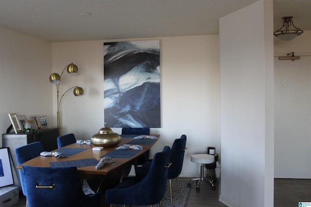 dining space with a textured ceiling and dark wood-type flooring