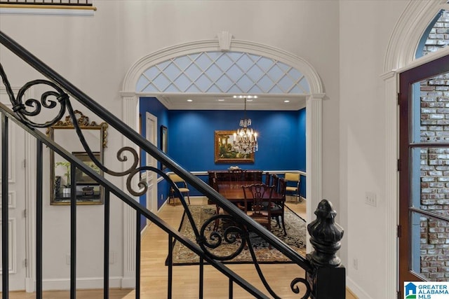 interior space featuring hardwood / wood-style flooring, ornamental molding, a high ceiling, and an inviting chandelier