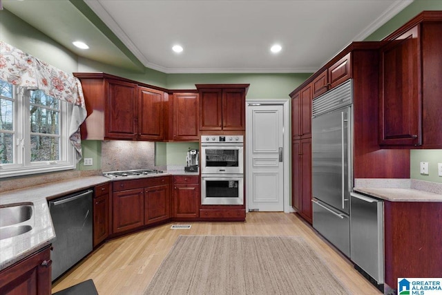 kitchen featuring backsplash, stainless steel appliances, light hardwood / wood-style flooring, and crown molding