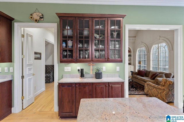 interior space with light hardwood / wood-style floors, dark brown cabinetry, and light stone countertops