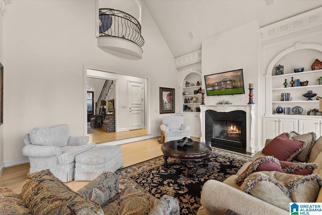 living room with high vaulted ceiling, light hardwood / wood-style floors, and built in features