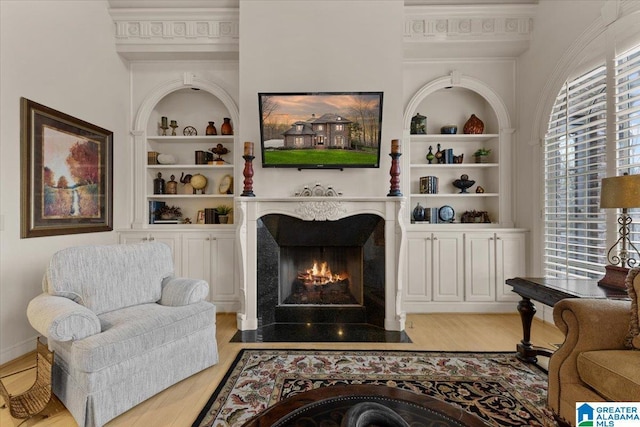 living room with crown molding, built in features, and light wood-type flooring