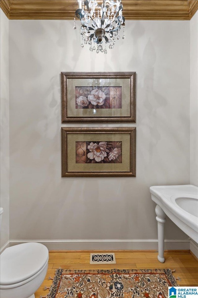 bathroom with crown molding, toilet, a notable chandelier, and hardwood / wood-style flooring