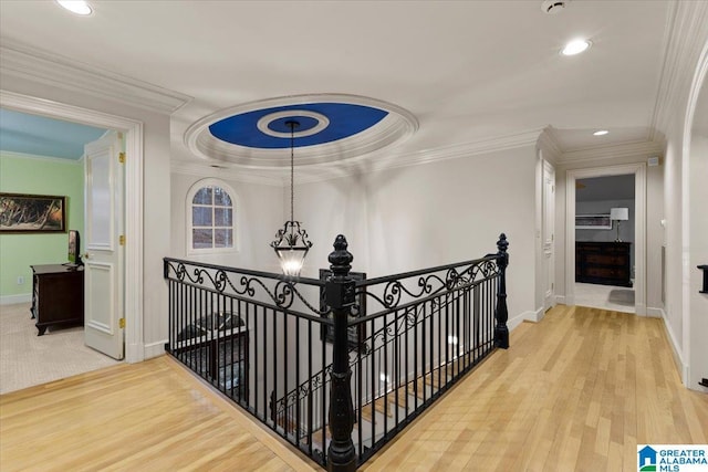 corridor with hardwood / wood-style floors, crown molding, and a chandelier