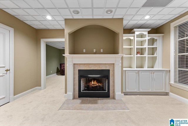 unfurnished living room featuring light colored carpet and a tile fireplace