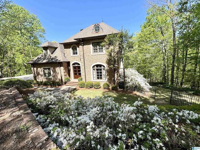 french country style house with fence and roof with shingles