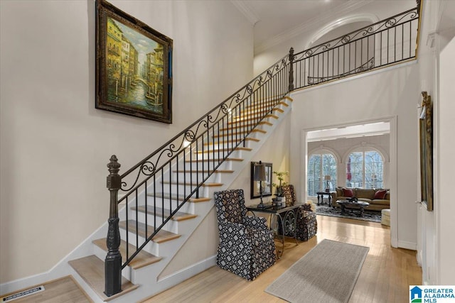 stairway with hardwood / wood-style flooring and crown molding