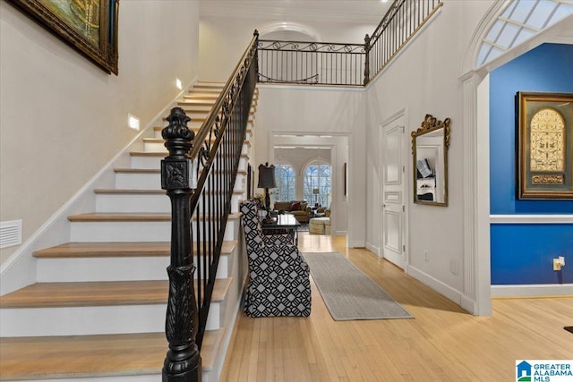 entryway featuring wood-type flooring and a towering ceiling