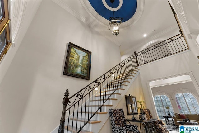 staircase with an inviting chandelier, a towering ceiling, and ornamental molding