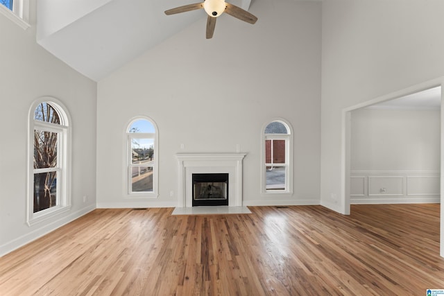 unfurnished living room featuring light wood-type flooring, high vaulted ceiling, and ceiling fan