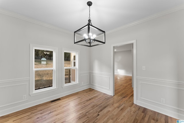 unfurnished dining area with crown molding, an inviting chandelier, and light hardwood / wood-style floors