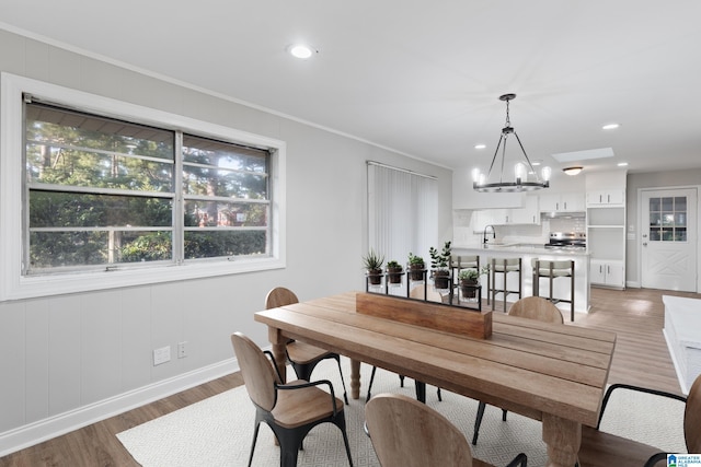 dining room with hardwood / wood-style flooring, a notable chandelier, ornamental molding, and sink