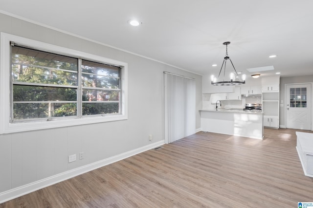 unfurnished living room with ornamental molding, hardwood / wood-style flooring, a notable chandelier, and sink