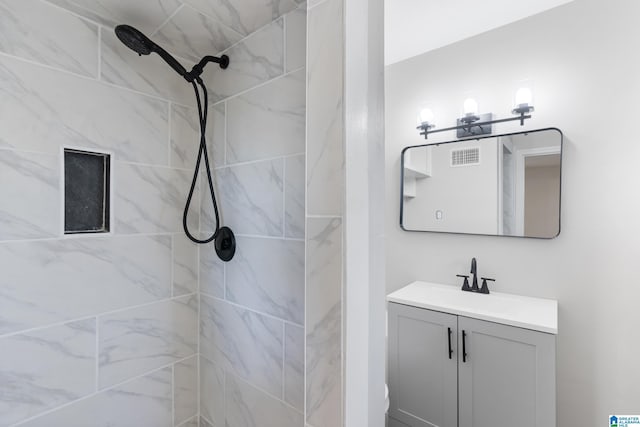 bathroom featuring a tile shower and vanity