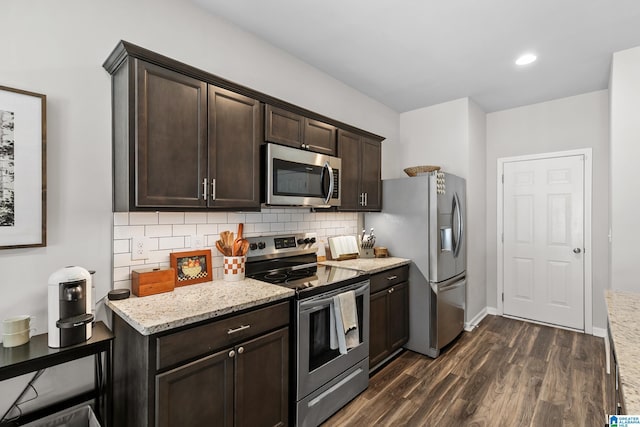 kitchen with light stone countertops, decorative backsplash, dark brown cabinets, and stainless steel appliances