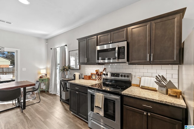 kitchen with decorative backsplash, light wood-type flooring, dark brown cabinetry, and stainless steel appliances